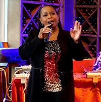 a woman singing into a microphone in front of a wine cellar