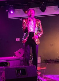 a man in a sequined suit singing on stage